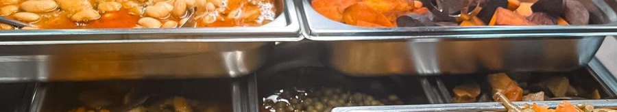 A buffet with various hot dishes in stainless steel containers, including beans, vegetables and stuffed eggplants., © Zauberküche, Stuttgart