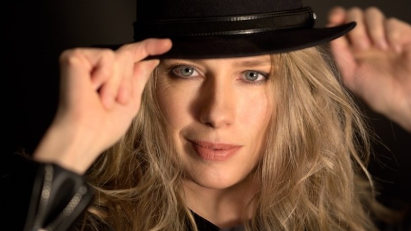 Eine Frau mit blonden Haaren trägt einen schwarzen Hut und eine Lederjacke. Sie schaut direkt in die Kamera und hält den Hut mit beiden Händen., © Renitenztheater Stuttgart e.V. Eine Frau mit blonden Haaren trägt einen schwarzen Hut und eine Lederjacke. Sie schaut direkt in die Kamera und hält den Hut mit beiden Händen., © Renitenztheater Stuttgart e.V.