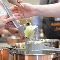 Several people use a potato ricer to press potatoes into a pot. More pots can be seen in the background., &copy; Ilzh&ouml;fer, Stuttgart