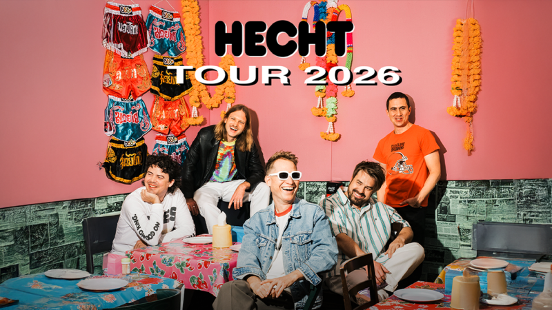 Die Band Hecht posiert fr&ouml;hlich vor einer bunten Wand mit Dekorationen. Der Text "Hecht Tour 2026" ist dar&uuml;ber gelegt., &copy; links im Bild