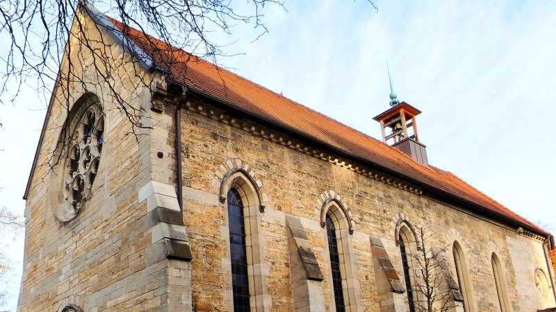 Steinkirche mit rotem Satteldach, Rundfenster und kleinem Glockenturm, von kahlen Ästen und Herbstbäumen umrahmt., © St. Katharina Stuttgart Steinkirche mit rotem Satteldach, Rundfenster und kleinem Glockenturm, von kahlen Ästen und Herbstbäumen umrahmt., © St. Katharina Stuttgart