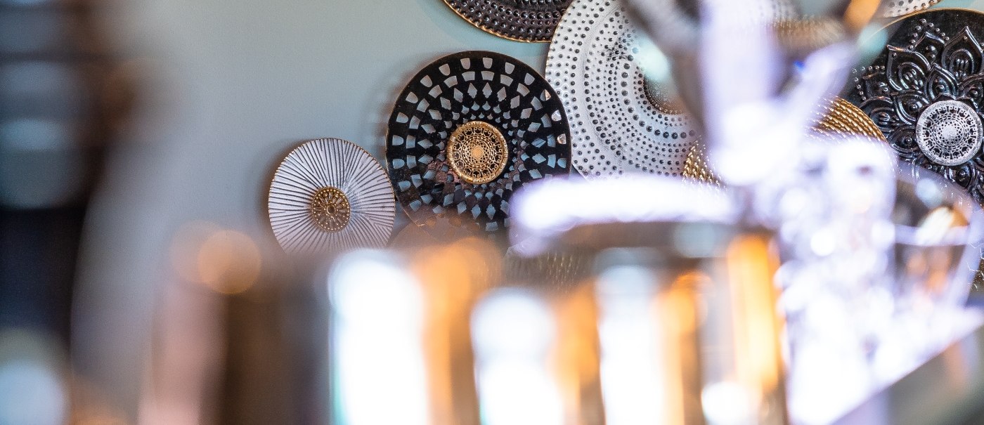 Decorative plates in gold, black and white on a wall. Blurred bar utensils in the foreground., &copy; MASEVEN Stuttgart SI-Centrum