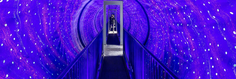 An illuminated tunnel with blue and violet lights in the Museum of Illusions in Stuttgart. A person stands at the end of the tunnel., © Stuttgart-Marketing GmbH, Sarah Schmid An illuminated tunnel with blue and violet lights in the Museum of Illusions in Stuttgart. A person stands at the end of the tunnel., © Stuttgart-Marketing GmbH, Sarah Schmid