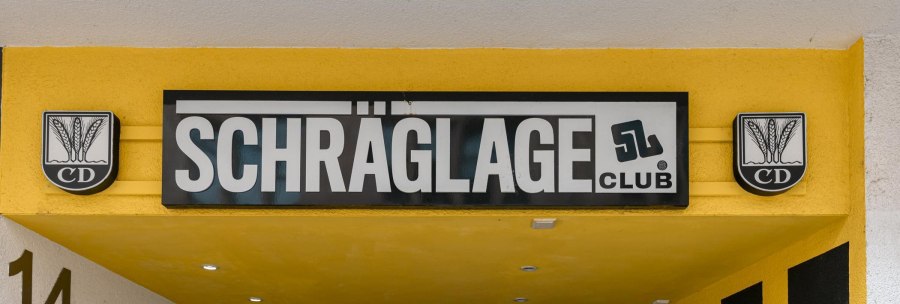 Entrance to the Schräglage Club with yellow façade and black sign. CD logos with ears of corn are depicted on the left and right., © Stuttgart Marketing GmbH, Sarah Schmid