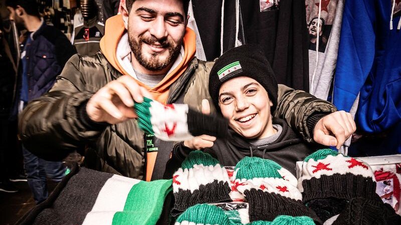 Die Sheikh Zayed Moschee in Abu Dhabi mit beeindruckender Architektur. Zwei Personen sind im Innenhof zu sehen, eine in traditioneller Kleidung, die andere beim Reinigen., &copy; Theaterhaus Stuttgart e.V.