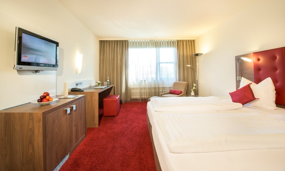 Modern double room with red carpet, double bed, flat-screen TV and desk. Light-colored curtains and an armchair complete the ambience., © Hotel Fuchsen Modern double room with red carpet, double bed, flat-screen TV and desk. Light-colored curtains and an armchair complete the ambience., © Hotel Fuchsen