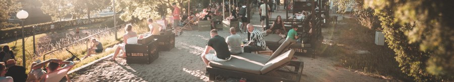 Menschen entspannen an einem sonnigen Stadtstrand in Stuttgart. Liegestühle und Sonnenschirme bieten eine gemütliche Atmosphäre im Sand., © Classic Rock Café Gastronomie- Betriebs GmbH