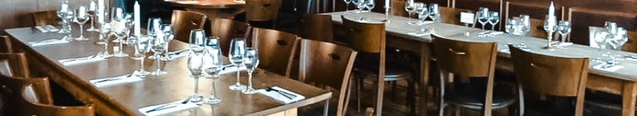 Elegant restaurant with wooden walls, laid tables and candlelight. Dark wooden furniture and a cozy atmosphere dominate the room., © Weinstube Fröhlich Verwaltungs GmbH
