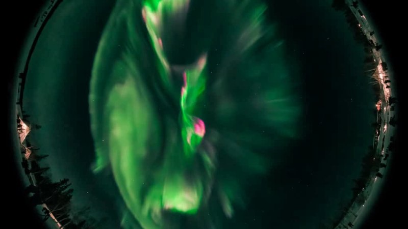 Fischaugenaufnahme von grünen und pinken Nordlichtern am Nachthimmel über Zelten und Bäumen., © Planetarium Stuttgart