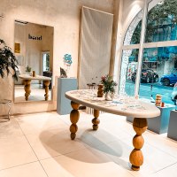 Modern studio with wooden table, mirror and decorations. Large window front with a view of the street. Plants and art objects as decoration., &copy; Goldmarlen