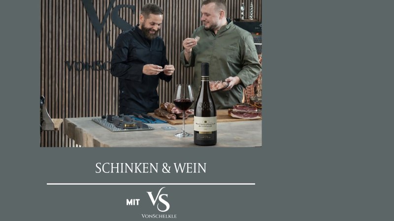 Two men are enjoying ham and wine at a table. A bottle of wine and a glass are in the foreground., © Weinmanufaktur Stuttgart eG Two men are enjoying ham and wine at a table. A bottle of wine and a glass are in the foreground., © Weinmanufaktur Stuttgart eG