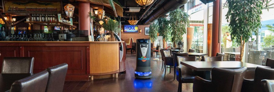 Ein Restaurant mit tropischer Dekoration, Holzmöbeln und einem Serviceroboter. Große Fenster lassen viel Licht herein, Pflanzen schmücken den Raum., © Palm Beach Stuttgart GmbH Ein Restaurant mit tropischer Dekoration, Holzmöbeln und einem Serviceroboter. Große Fenster lassen viel Licht herein, Pflanzen schmücken den Raum., © Palm Beach Stuttgart GmbH