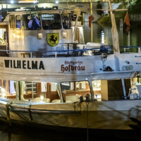 Das Ausflugsschiff liegt beleuchtet am Flussufer. Es tr&auml;gt das Logo von Stuttgarter Hofbr&auml;u und ist f&uuml;r Partys oder Feiern ausgestattet., &copy; NeckarFlair MS Wilhelma Betriebsgesellschaft mbH
