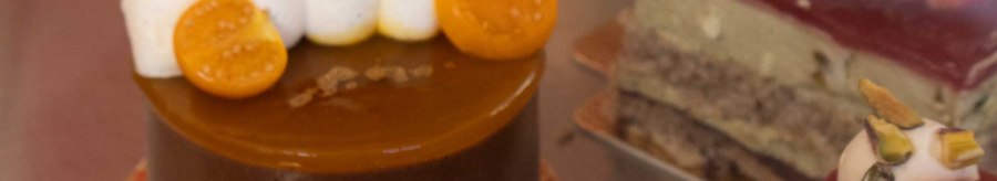 Close-up of artfully decorated cakes in a display case. Various toppings such as fruit and cream can be seen., &copy; SMG