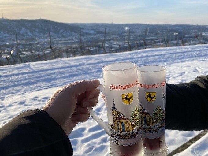 Zwei Personen stoßen mit Glühweintassen an, im Hintergrund verschneite Weinberge in Stuttgart., © Weingenuss Stuttgart Zwei Personen stoßen mit Glühweintassen an, im Hintergrund verschneite Weinberge in Stuttgart., © Weingenuss Stuttgart