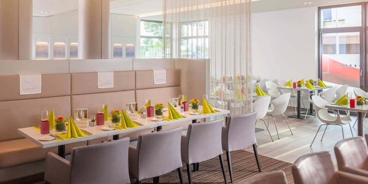 Modernes Restaurant mit eleganter Einrichtung, gedeckten Tischen mit gr&uuml;nen Servietten und stilvollen St&uuml;hlen. Helle, freundliche Atmosph&auml;re., &copy; Essential by Dorint