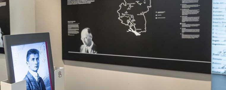 A historical photo in an exhibition room, a map in the background and text panels on the wall., © Haus der Geschichte Baden-Württemberg