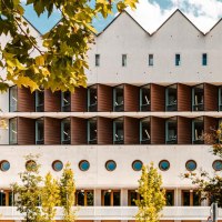 Modern library with a striking geometric fa&ccedil;ade, surrounded by trees. A black pillar with graffiti is visible on the right of the picture., &copy; SMG Stuttgart Marketing GmbH - Sarah Schmid