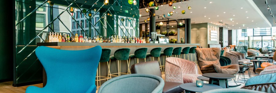 Moderne Lobby mit eleganten Sesseln, Barhockern und einer Bar im Hintergrund. Dekorative Beleuchtung und stilvolle Einrichtung., &copy; Motel One - Stuttgart Hauptbahnhof