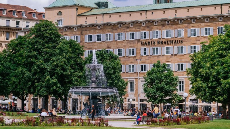 Belebter Schlossplatz mit Brunnen, umgeben von Bäumen und Menschen. Im Hintergrund ein Gebäude mit 'Carls Brauhaus'., © Thomas Niedermüller Belebter Schlossplatz mit Brunnen, umgeben von Bäumen und Menschen. Im Hintergrund ein Gebäude mit 'Carls Brauhaus'., © Thomas Niedermüller