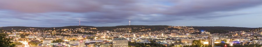 Panorama einer Stadt bei Abenddämmerung, mit beleuchteten Gebäuden und einem bewölkten Himmel im Hintergrund., © SMG, Werner Dieterich
