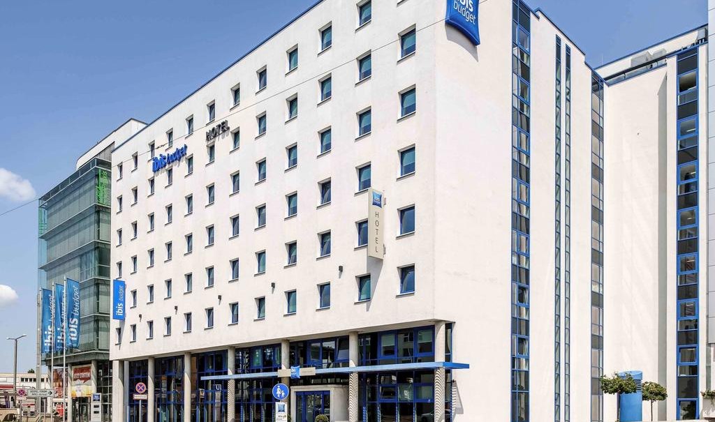 The ibis budget Stuttgart City Nord is a modern, white building with blue accents and lots of windows. It is located on a busy street., © ibis budget Stuttgart City Nord The ibis budget Stuttgart City Nord is a modern, white building with blue accents and lots of windows. It is located on a busy street., © ibis budget Stuttgart City Nord