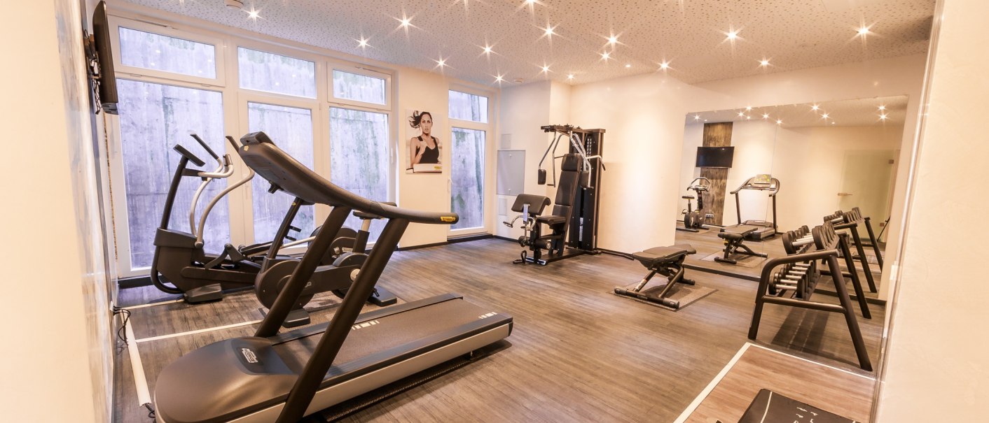 Bright fitness room with treadmill, weights and strength equipment. Large windows and mirrors on the walls. Ceiling lighting creates a pleasant atmosphere., © PLAZA Hotelgroup GmbH