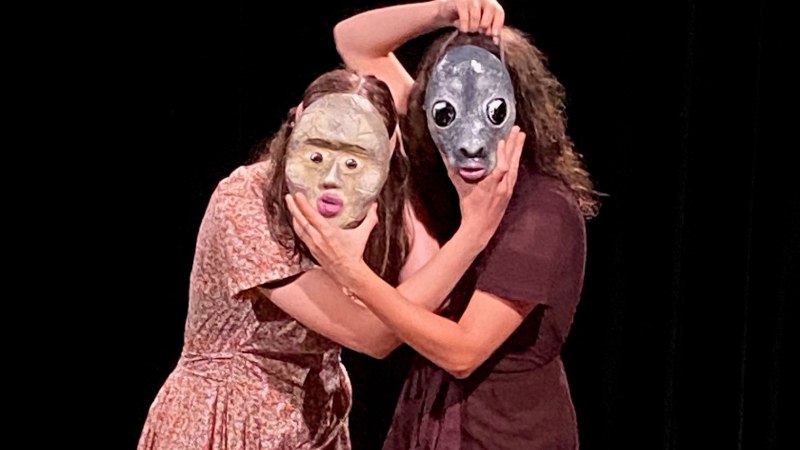 Zwei Personen auf einer B&uuml;hne tragen kunstvolle Masken. Die Masken haben gro&szlig;e Augen und ausdrucksstarke Gesichter. Der Hintergrund ist schwarz., &copy; Wilhelma Theater
