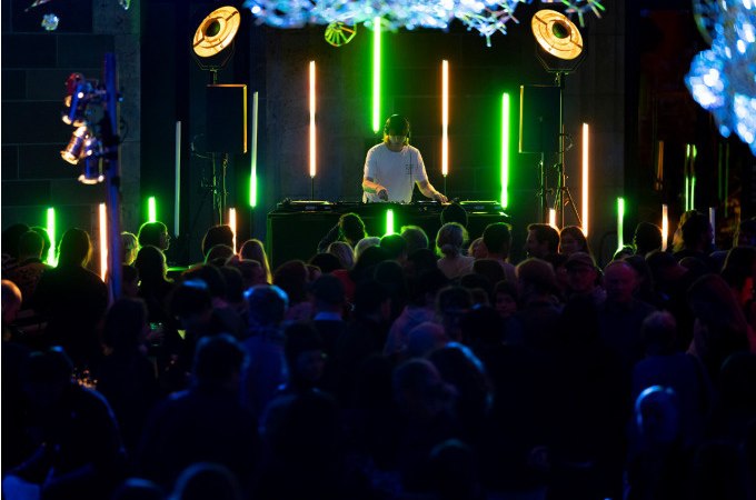 A DJ is performing in a club with colorful lights and a dancing crowd., &copy; Landesmuseum W&uuml;rttemberg