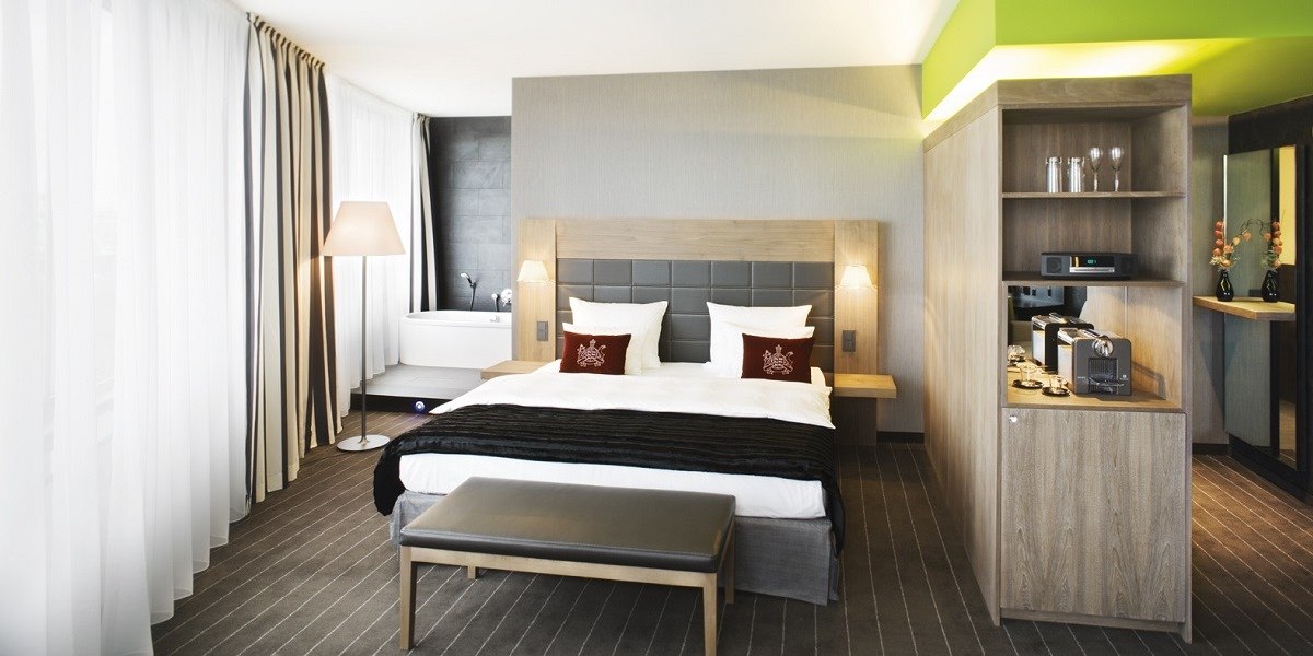 Moderne Junior Suite mit Doppelbett, Badewanne, Kaffeemaschine und eleganter Einrichtung. Große Fenster mit Vorhängen, stilvolle Beleuchtung., © Mövenpick Hotel Stuttgart Airport Moderne Junior Suite mit Doppelbett, Badewanne, Kaffeemaschine und eleganter Einrichtung. Große Fenster mit Vorhängen, stilvolle Beleuchtung., © Mövenpick Hotel Stuttgart Airport