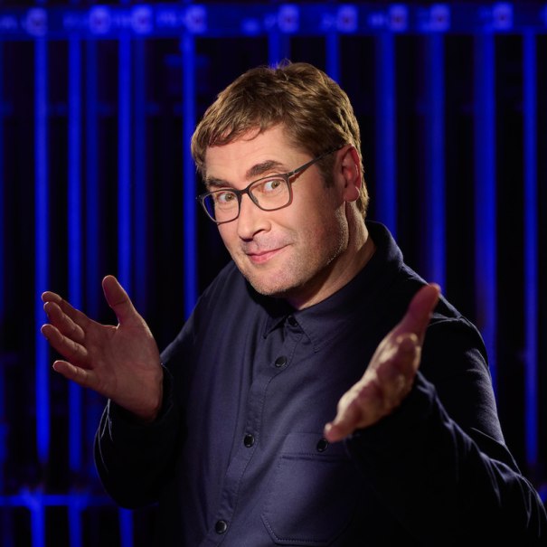 Ein Mann mit Brille und dunklem Hemd gestikuliert vor einem blauen Hintergrund. Er wirkt freundlich und selbstbewusst., © Renitenztheater Stuttgart e.V. Ein Mann mit Brille und dunklem Hemd gestikuliert vor einem blauen Hintergrund. Er wirkt freundlich und selbstbewusst., © Renitenztheater Stuttgart e.V.