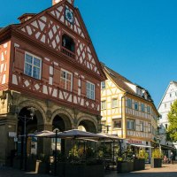 Historic half-timbered building on the market square in Waiblingen, surrounded by other half-timbered houses and an outdoor café in sunny weather., © Stuttgart-Marketing GmbH, Sarah Schmid