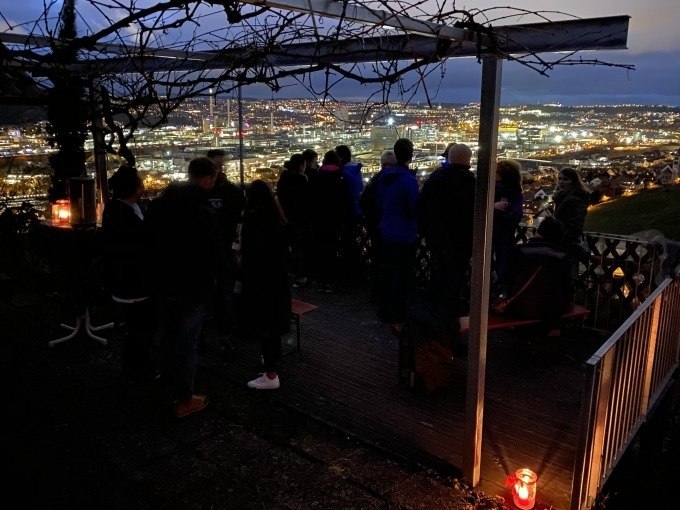 Menschen stehen auf einer Terrasse mit Blick auf das nächtliche, beleuchtete Stuttgart. Kerzen sorgen für stimmungsvolle Beleuchtung., © Weingenuss Stuttgart Menschen stehen auf einer Terrasse mit Blick auf das nächtliche, beleuchtete Stuttgart. Kerzen sorgen für stimmungsvolle Beleuchtung., © Weingenuss Stuttgart