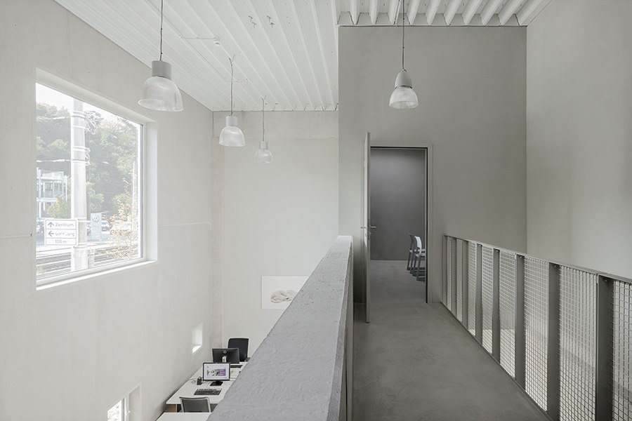 Modernes Büro mit hohen Decken, großen Fenstern und minimalistischer Einrichtung. Ein Flur führt zu einem offenen Raum mit Schreibtischen., © club traube Modernes Büro mit hohen Decken, großen Fenstern und minimalistischer Einrichtung. Ein Flur führt zu einem offenen Raum mit Schreibtischen., © club traube