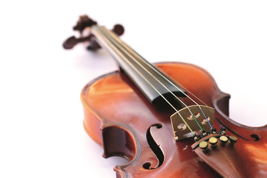 Nahaufnahme einer Violine, die auf einem wei&szlig;en Hintergrund liegt. Die Saiten und der Korpus sind deutlich sichtbar., &copy; Shutterstock
