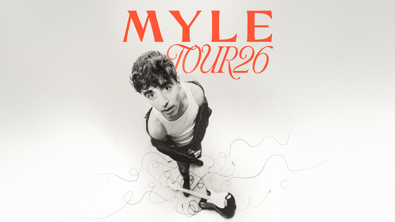 Ein Musiker in einem wei&szlig;en Tanktop und schwarzer Jacke steht mit einer Gitarre auf dem Boden. Der Schriftzug 'MYLE Tour 26' ist oben zu sehen., &copy; links im Bild