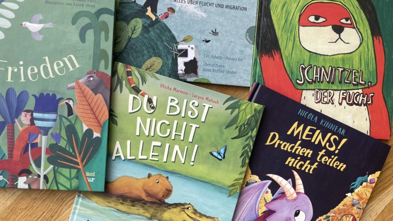 F&uuml;nf Kinderb&uuml;cher mit farbenfrohen Covern liegen auf einem Holztisch und laden zum Lesen ein., &copy; Labyrinth
