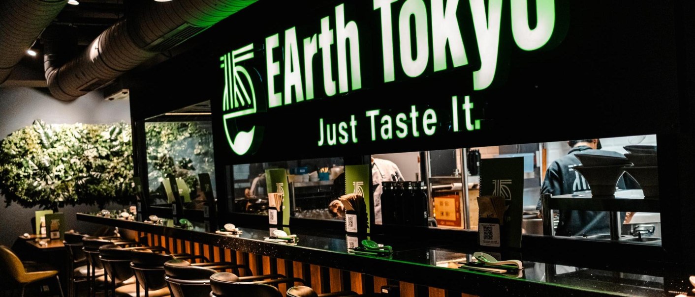 Restaurant mit dem Schild 'EArth Tokyo' und dem Slogan 'Just Taste It'. Moderne Einrichtung mit Pflanzenwand und Theke., © Stuttgart Marketing GmbH - Sarah Schmid