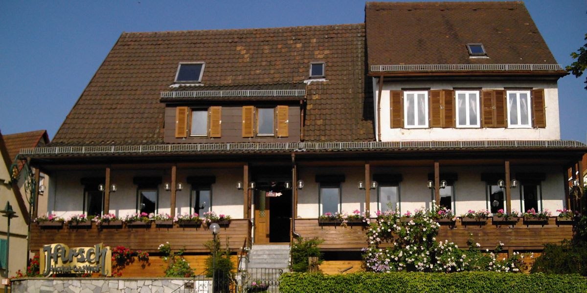 Ein traditionelles Gasthaus mit braunem Dach und Fensterläden. Der Balkon ist mit Blumen geschmückt. Der Schriftzug 'Hirsch' ist sichtbar., © Hotel Gasthof Hirsch Ein traditionelles Gasthaus mit braunem Dach und Fensterläden. Der Balkon ist mit Blumen geschmückt. Der Schriftzug 'Hirsch' ist sichtbar., © Hotel Gasthof Hirsch