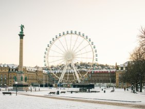 Winterlicher Schlossplatz in Stuttgart mit schneebedecktem Boden, einer hohen S&auml;ule und einem gro&szlig;en Riesenrad vor einem Schloss, im Hintergrund., &copy; Stuttgart-Marketing GmbH, Sarah Schmid