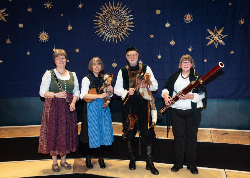 Vier Personen in Tracht mit Musikinstrumenten vor blauem Hintergrund mit Sternendekoration., &copy; Peter Oehl