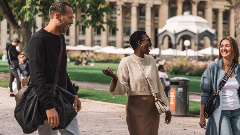 Drei Personen spazieren lachend im Oberen Schlossgarten. Im Hintergrund sind Bäume, ein Pavillon und ein Gebäude mit Säulen zu sehen., © SMG, wpsteinheisser Drei Personen spazieren lachend im Oberen Schlossgarten. Im Hintergrund sind Bäume, ein Pavillon und ein Gebäude mit Säulen zu sehen., © SMG, wpsteinheisser