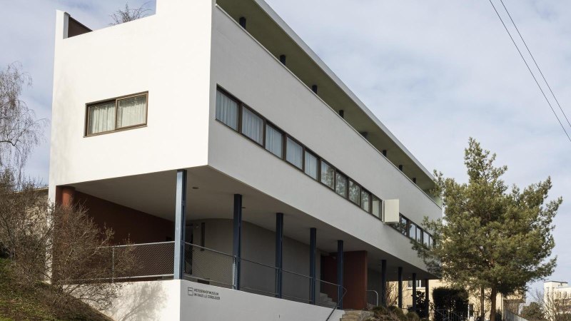 Modernes Geb&auml;ude mit wei&szlig;er Fassade und gro&szlig;en Fenstern, umgeben von B&auml;umen und einem Plakatst&auml;nder., &copy; Stuttgart Marketing GmbH, Sarah Schmid