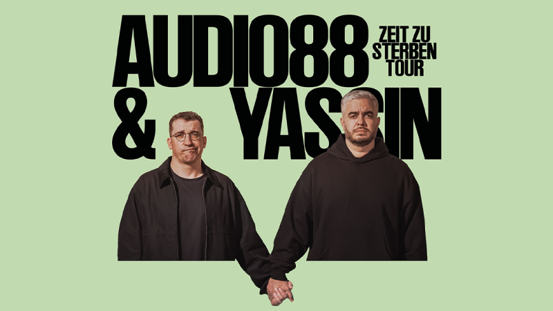 Zwei Männer halten sich an den Händen vor einem grünen Hintergrund. Der Text 'Audio88 & Yassin - Zeit zu sterben Tour' ist darüber zu sehen., © links im Bild Zwei Männer halten sich an den Händen vor einem grünen Hintergrund. Der Text 'Audio88 & Yassin - Zeit zu sterben Tour' ist darüber zu sehen., © links im Bild