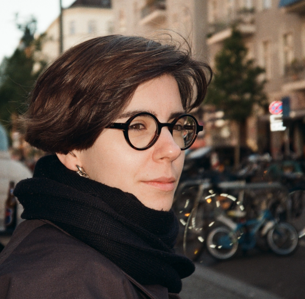 Eine Person mit Brille und schwarzem Schal steht in einer st&auml;dtischen Umgebung. Im Hintergrund sind Fahrr&auml;der und Geb&auml;ude zu sehen., &copy; privat