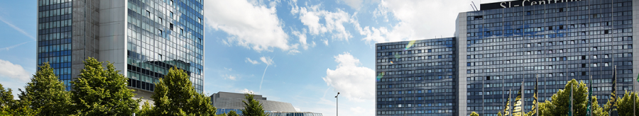 Moderne Gebäude des SI-Centrums mit Glasfassaden, umgeben von Bäumen, unter einem blauen Himmel mit Wolken., © Susanne Wegner Photography