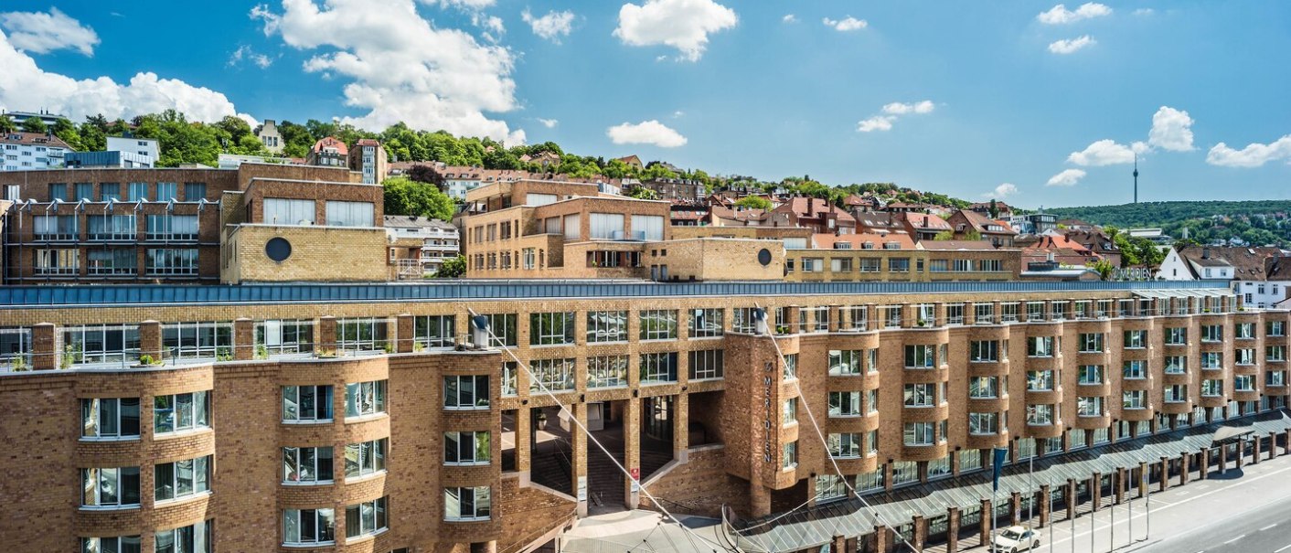 The Le Méridien Hotel in Stuttgart with its striking architecture, surrounded by green hills and under a clear blue sky., © Hotel Le Méridien The Le Méridien Hotel in Stuttgart with its striking architecture, surrounded by green hills and under a clear blue sky., © Hotel Le Méridien