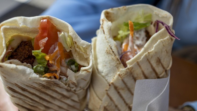 Zwei frisch gegrillte Wraps, gef&uuml;llt mit Falafel, Salat, Tomaten und Joghurtso&szlig;e, werden in der Hand gehalten. Die knusprigen Fladenbrote sind mit Grillstreifen versehen. Die Wraps sind im Fokus, im Hintergrund verschwommen erkennt man die blauen &Auml;rmel der Person, die die Wraps h&auml;lt. , &copy; Stuttgart-Marketing GmbH, Sarah Schmid