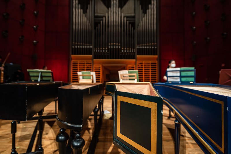 Several harpsichords stand in a room with a large organ in the background. A person wearing a mask can be seen in the background., &copy; Staatliche Hochschule f&uuml;r Musik und Darstellende Kunst