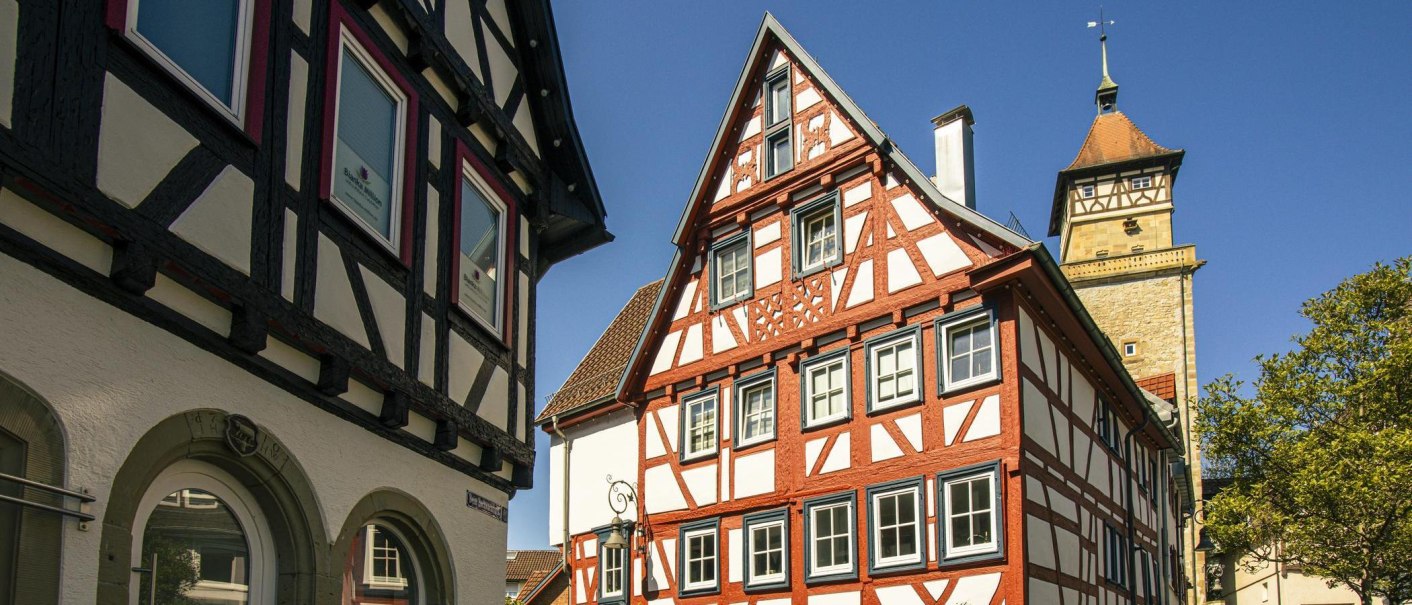 Half-timbered houses in Waiblingen with a striking tower in the background, under a blue sky., © SMG Stuttgart Marketing GmbH - Sarah Schmid